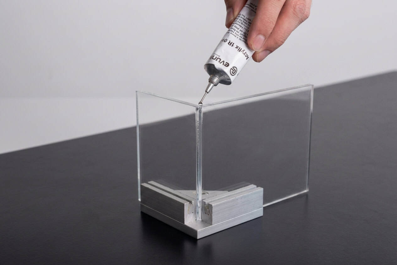 Zwei kleine Polycarbonatzuschnitte, welche mit einem geeigneten Klebstoff verklebt werden.
