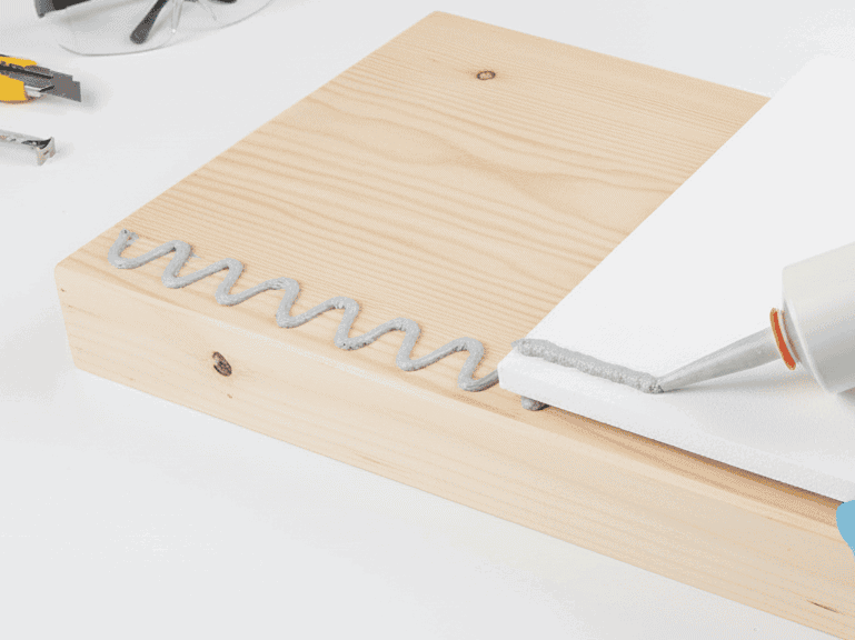 Klebstoff wird sowohl auf einem Stück Holz sowie einer PVC Hartschaumplatte aufgetragen um diese dauerhaft miteinander zu verkleben